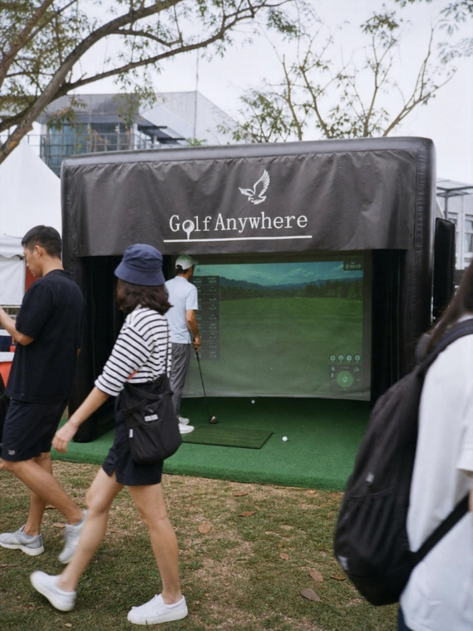 Guest taking a swing at the Golf Anywhere simulator at an outdoor campus event